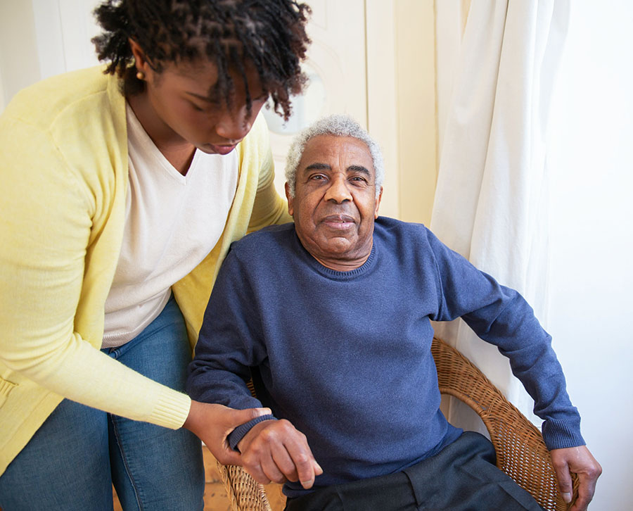 Caregiver assisting a guest sitting in a chair