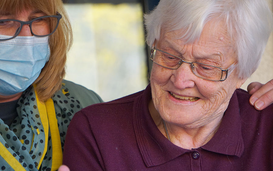 Caregiver placing her arm around a guest