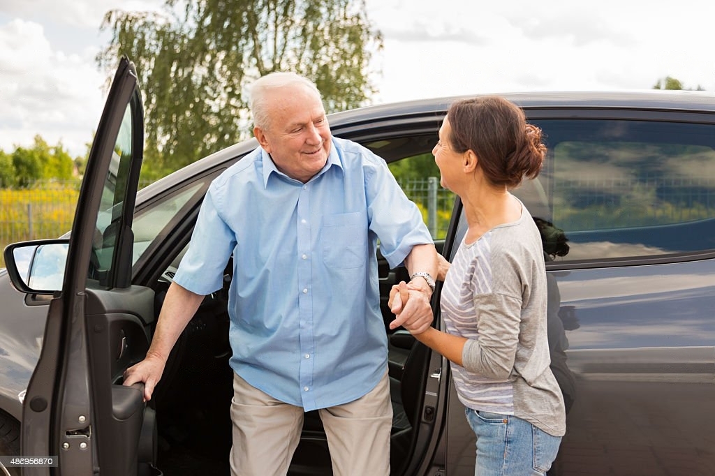 Caregiver helping a senior out of a car